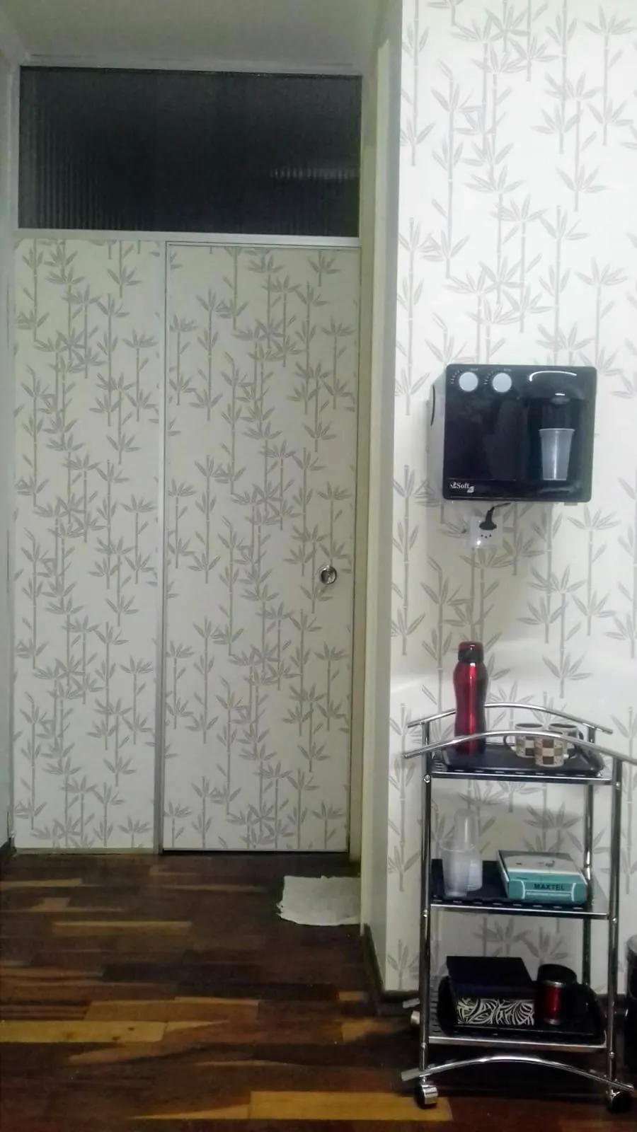 Purificador de água preto instalado em parede com papel de parede de bambu